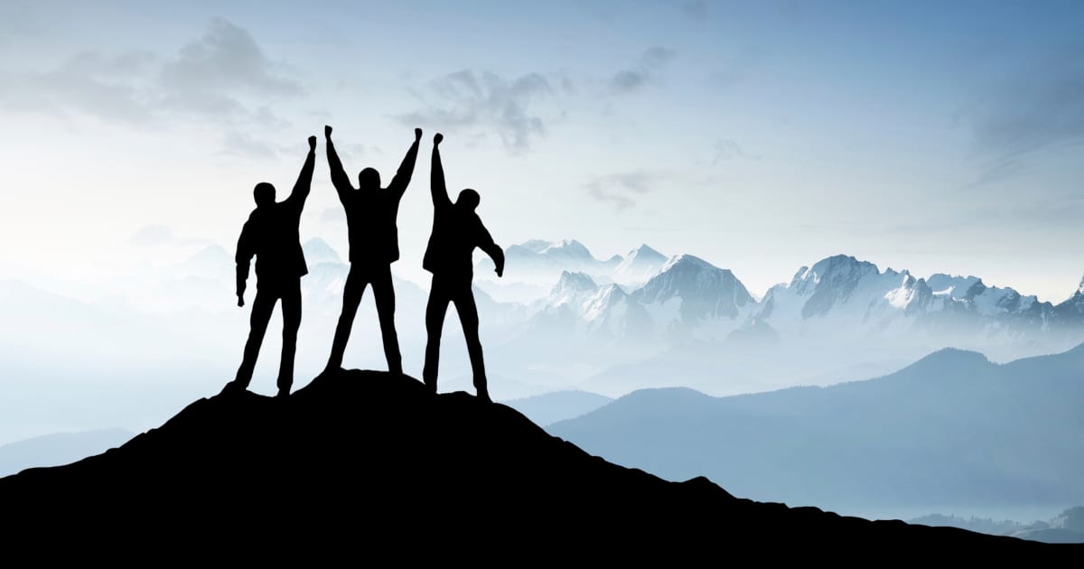 three silhouettes of people with hands raised up on top of mountain