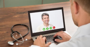 doctor and patient conversing via laptop